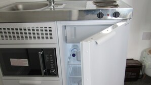 A compact kitchenette with a sink, microwave, and refrigerator. - Cozy Studio Rental With Private Facilities in Greater London (Welling)