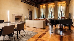 Un salón espacioso con un piano de cola, una chimenea y un gran comedor.