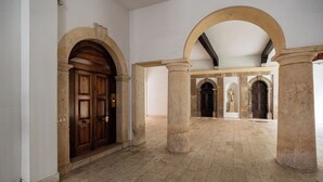 Un interior con arcos, columnas y suelo de baldosas.