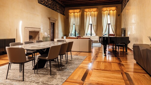 Una habitación amplia con una mesa de mármol, sillas, un piano y un sofá.