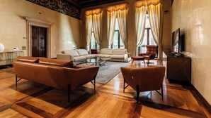 Una sala de estar con un sofá, dos sillones, una mesa de centro y un televisor.