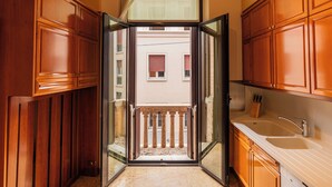 Una cocina con armarios de madera, un lavamanos y una puerta abierta que da a un balcón.