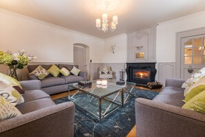 Una sala de estar con chimenea, una mesa de centro de vidrio y dos sofás.