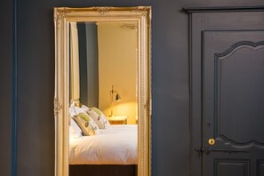 Un dormitorio con cama, almohadas, mesita de noche y lámpara.