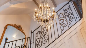 Una escalera con barandillas de metal decoradas y una araña.