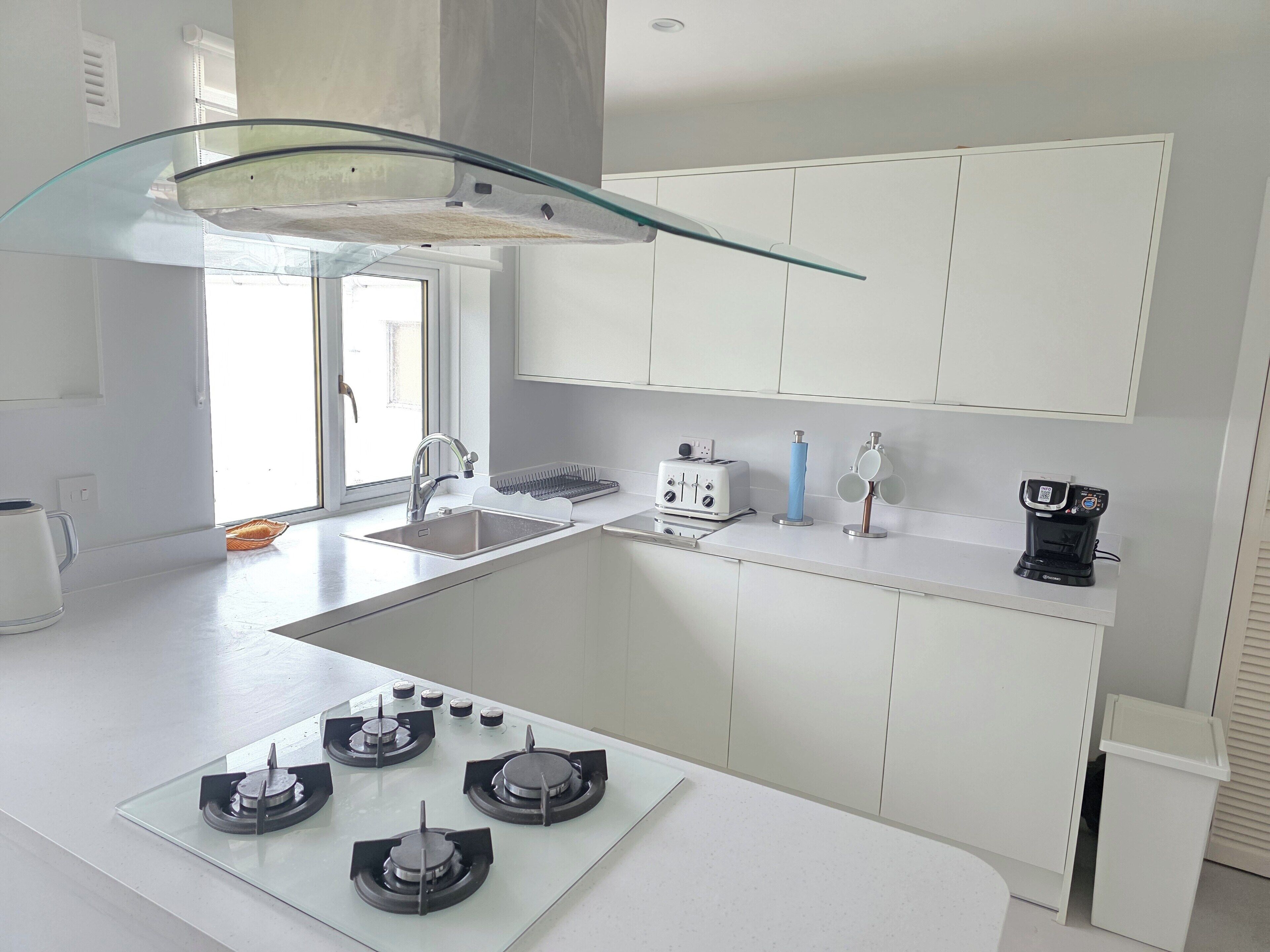 A modern kitchen with a glass-top island, a gas stove, a toaster, and a coffee maker.