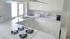 A modern kitchen with a glass-top island, a gas stove, a toaster, and a coffee maker.