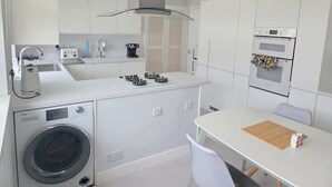 A compact kitchen with a washing machine, a coffee maker, a toaster, and an oven.