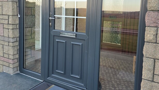 A grey double door with a window, a welcome sign, and a number '10' on the wall.