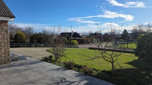 A residential area with a paved driveway, a grassy lawn, and a stone building.