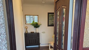 A hallway with a dark wooden door, a radiator, a bench, a mirror, and a framed picture on the wall.