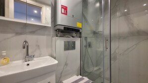 Et moderne badeværelse med bruseniche, et hvidt håndvaskarmatur i krom og et toilet med et håndklæde.