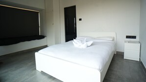 Une chambre à coucher moderne avec un grand lit, une table de chevet, une armoire et un banc intégré le long du mur.