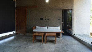 Une pièce comprenant un lit, deux tables de chevet en bois, une armoire en bois et un plancher en béton.