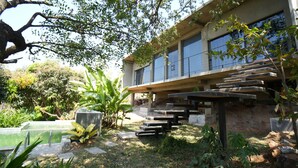 Un bâtiment moderne doté d’un toit plat, de grandes fenêtres et d’un escalier en béton menant à une zone abritée.