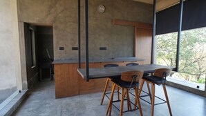 Une cuisine moderne dotée d’un grand îlot central, de chaises en bois et offrant une vue dégagée grâce à de grandes fenêtres.