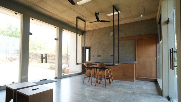 Un intérieur moderne comprenant un coin repas, de grandes fenêtres et un ventilateur de plafond.