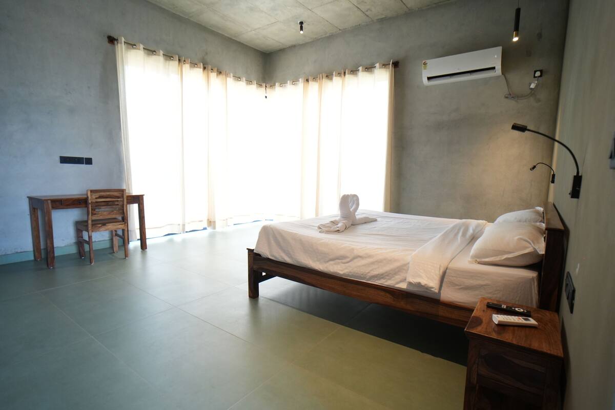 A bedroom with a bed, a chair, a desk, and an air conditioning unit.