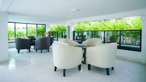 Un espacio interior amplio con techo alto, ventanas grandes y vistas al verdor exterior.