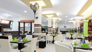 Restaurante com várias mesas, cadeiras e um ventilador.