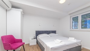 Ein Schlafzimmer mit einem Bett, einem Nachttisch, einem Sessel und einem Fenster.