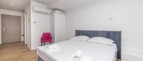 Ein modernes Hotelzimmer mit einem großen Bett, einem Schrank, einem Sessel und einer Klimaanlage.