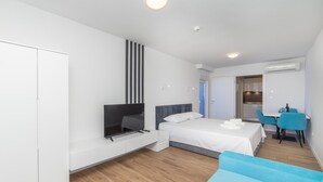 A modern bedroom with a bed, a TV, a desk, and a dining area. - Altiora Prestige Residence 103 (Gradac)