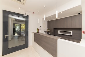 A modern kitchen with a dark wood countertop, a glass door, and a built-in wine rack. - Altiora Prestige Residence 304 (Gradac)