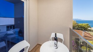 Een balkon met een tafel, stoelen, een fles wijn en een glas.