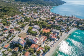 Luftaufnahme einer Küstenstadt mit Wohnhäusern, einem Strand und einem klaren, blauen Meer.