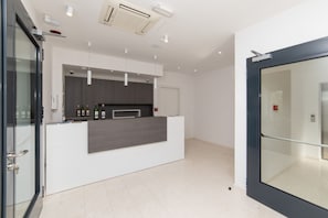 A modern kitchen with a white countertop, dark cabinets, and a glass door leading to a hallway. - Altiora Prestige Residence 301 (Gradac)