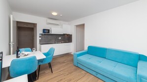 Eine moderne Küche mit weißen Schränken, einer grauen Arbeitsplatte und einem blauen Sofa.