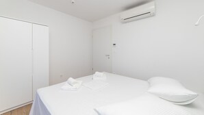 Ein sauberes, modernes Hotelzimmer mit einem ordentlich bezogenen Bett, einer Klimaanlage und einer Tür.