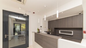 Een moderne keuken met een donker houten aanrecht, een glazen deur en een ingebouwde wijnkast.