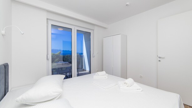 Een moderne slaapkamer met een bed, een kledingkast en een balkon met uitzicht.