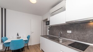 Een moderne keuken met witte kasten, een grijze spatwand, een ingebouwde magnetron en een roestvrijstalen spoelbak.