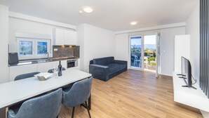 A modern kitchen with a dining area, a sofa, and a TV. - Altiora Prestige Residence 101 (Gradac)