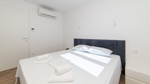 A clean, modern hotel room with a neatly made bed, an air conditioning unit, and a door with a handle. - Altiora Prestige Residence 101 (Gradac)