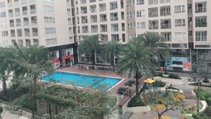 A high-rise residential building with multiple balconies, a swimming pool, and a playground. - Luxury 2 bedroom Apartment Sky Center (Ho Chi Minh City)
