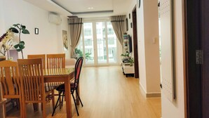 A dining area with wooden chairs and a table, a ceiling light, and a view through a glass door to the outside. - Luxury 2 bedroom Apartment Sky Center (Ho Chi Minh City)