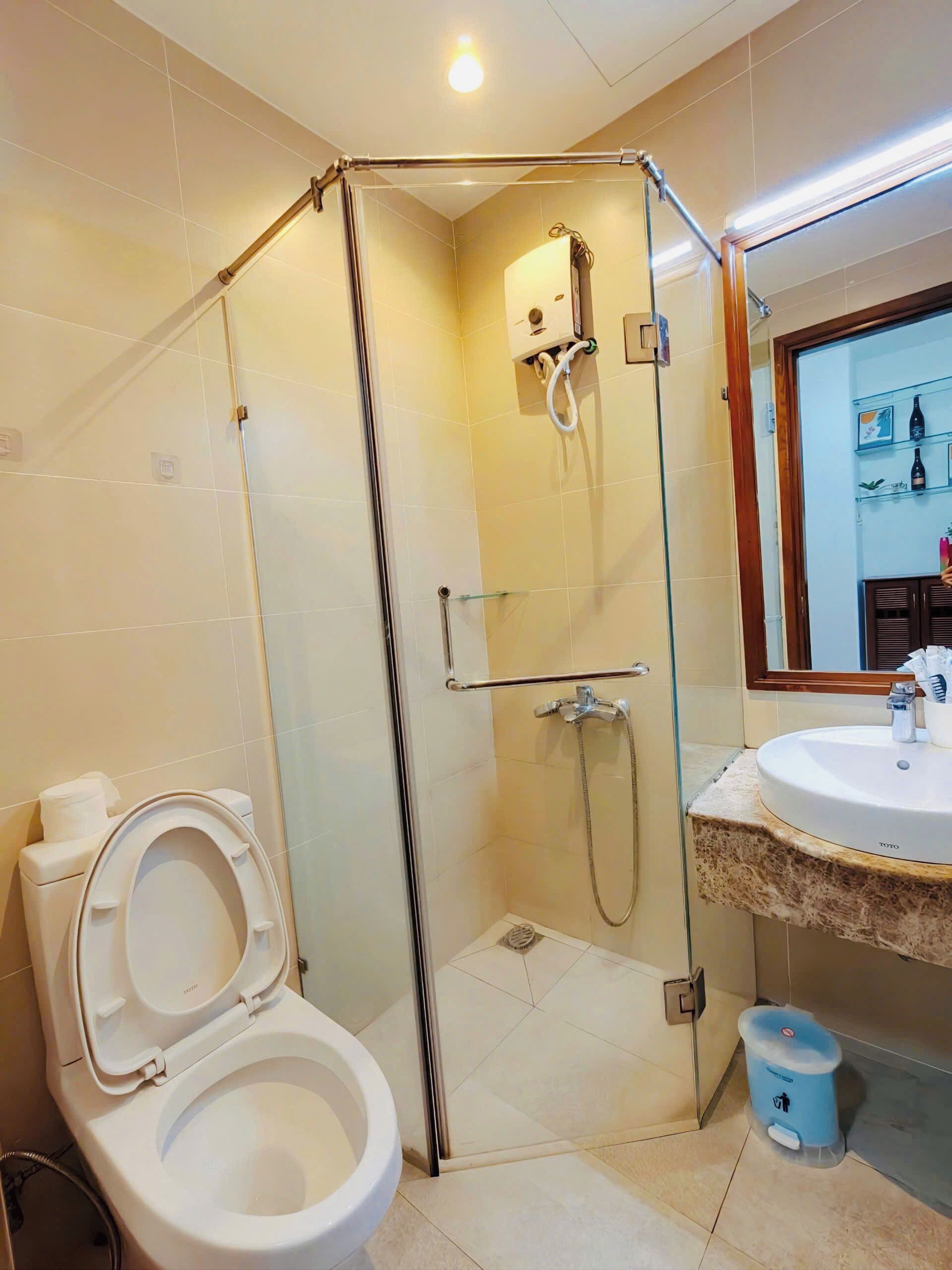 Une salle de bain dotée d’une douche à parois de verre, de toilettes et d’un lavabo avec un plan de travail en marbre.