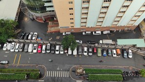 An aerial view of a parking lot with multiple cars and a few motorcycles, surrounded by buildings with balconies and a green area with plants. - Luxury 2 bedroom Apartment Sky Center (Ho Chi Minh City)