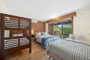 A room with two beds, a brick wall, and large windows. - Multi-Family Coastal Escape | Camp & Stay (St Leonards)