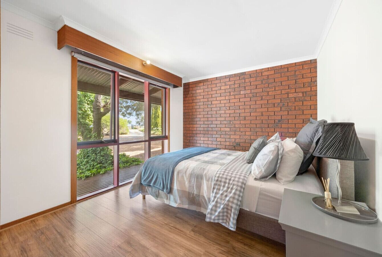 Een slaapkamer met een bed, een nachtkastje, een lamp en uitzicht door een schuifdeur.