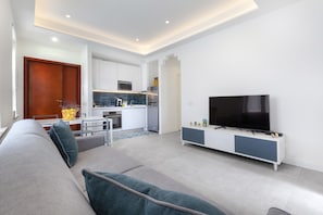 A modern living room with a sofa, a television, and a kitchen in the background. - CASA APREDA (Sorrento)