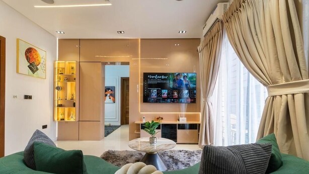 A modern living room with a sofa, a coffee table, a TV, and a decorative shelf. - Primehomes  (Lekki)
