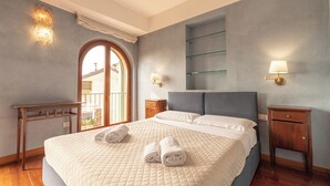 A bedroom with a bed, two bedside tables, a nightstand, a wall-mounted shelf, and a window with a view. - Residenza vista mozzafiato Ponte Pietra (Verona)