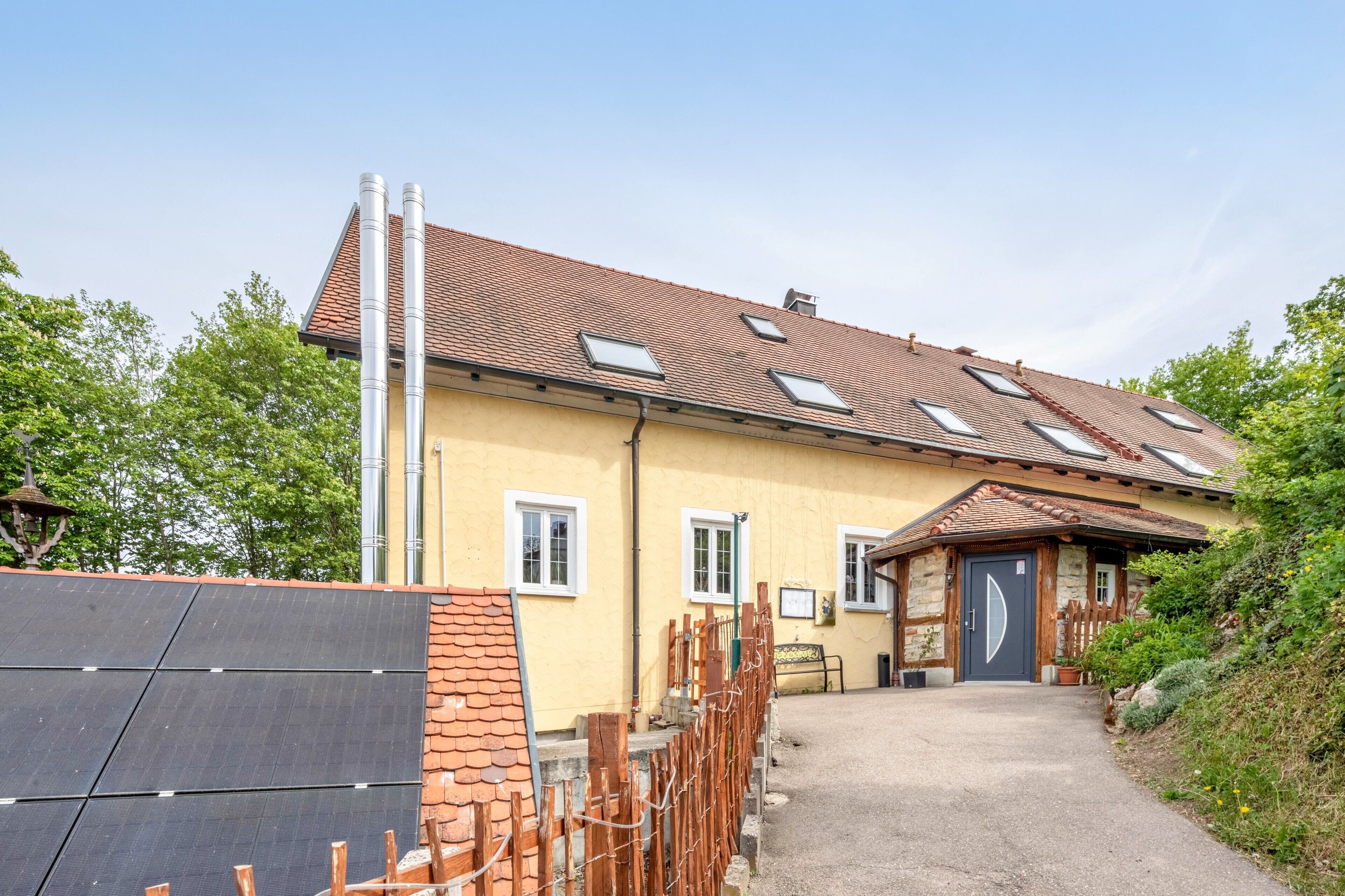Un bâtiment jaune avec un toit recouvert de tuiles, de nombreuses fenêtres et une porte.