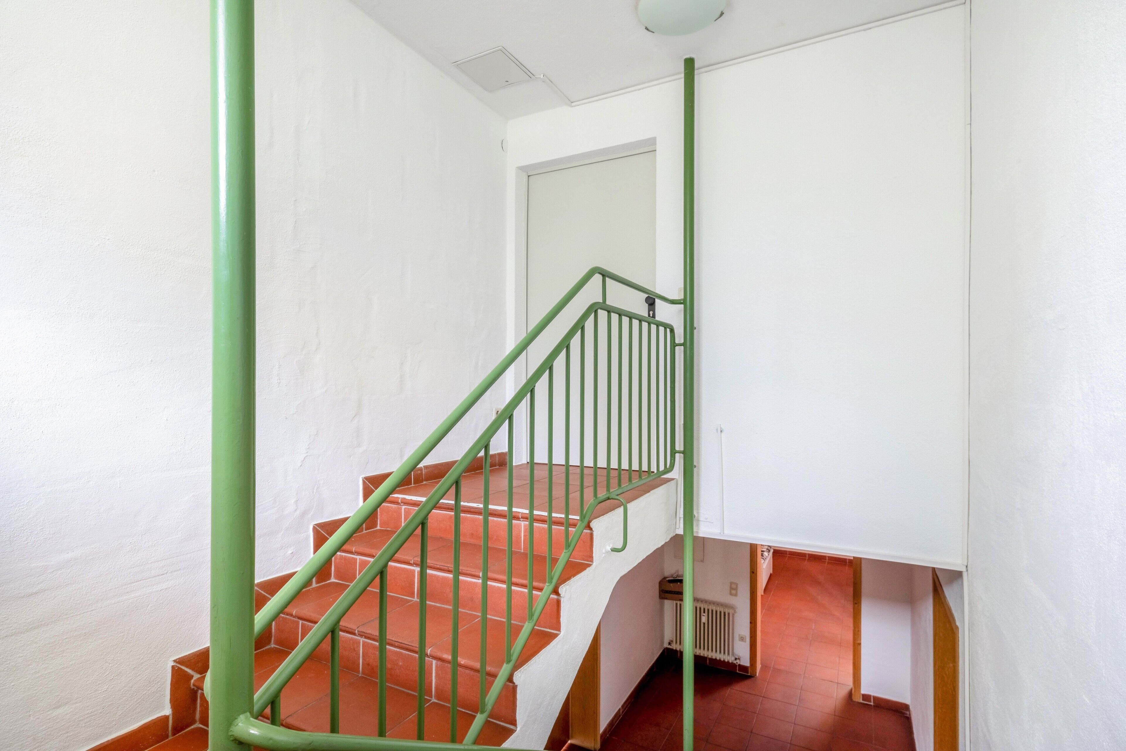 A staircase with green railings and terracotta steps.