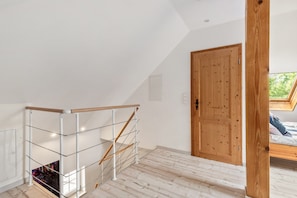 A room with a wooden door, a window, and a white wall.